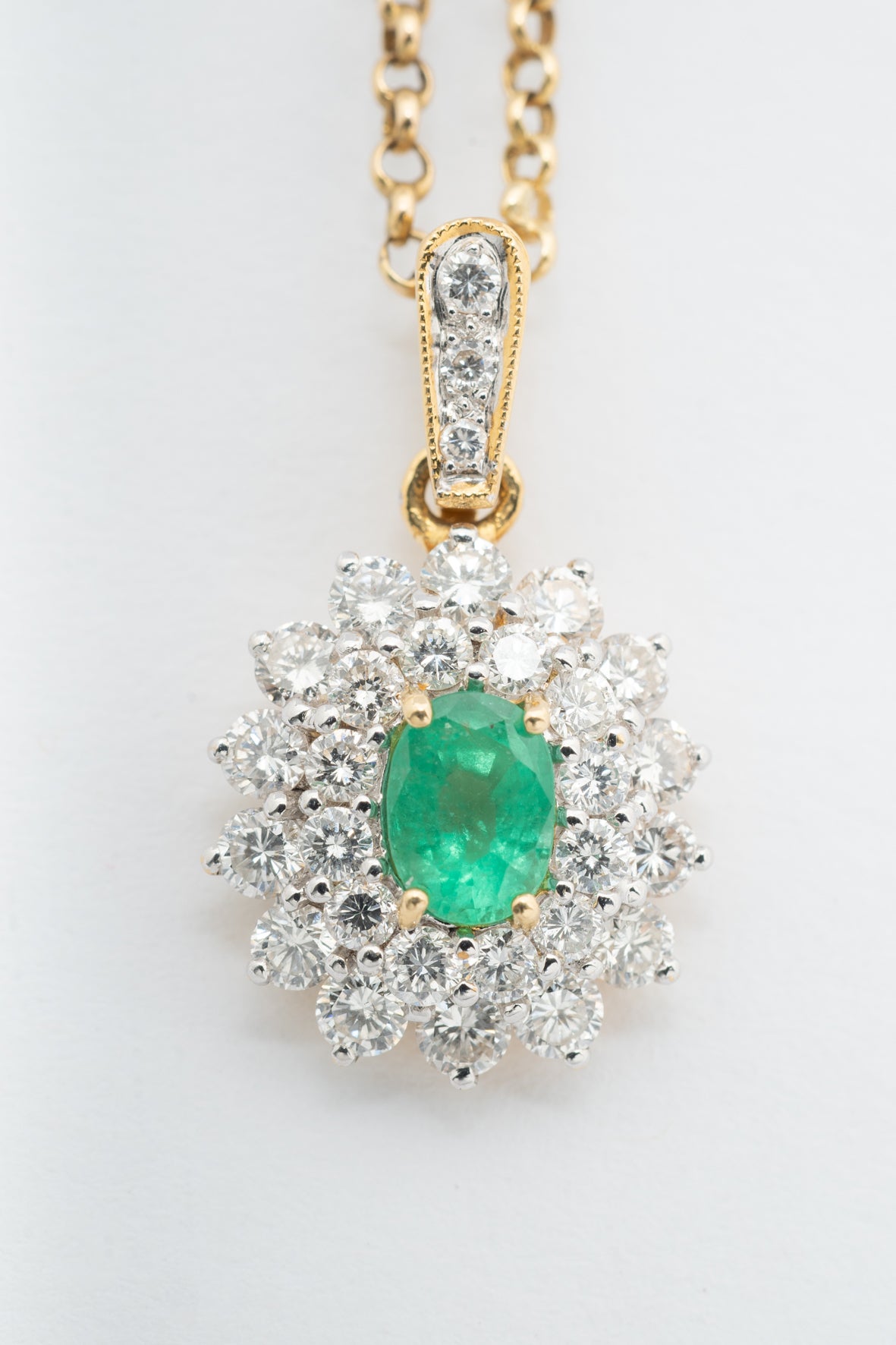 Yellow gold double cluster pendant with emerald and brilliant cut diamonds on a yellow gold necklace