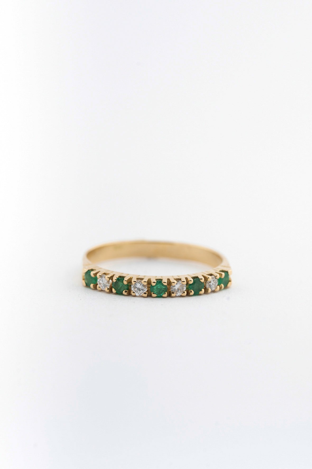 Yellow gold eternity ring with emeralds and brilliant cut diamonds