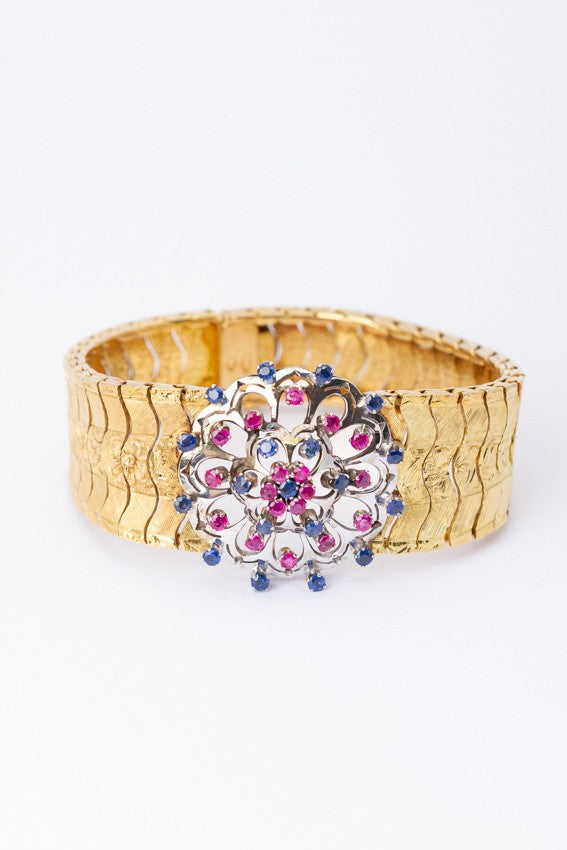 Gouden schakel armband met in het midden een wit gouden rozet met robijnen en saffieren