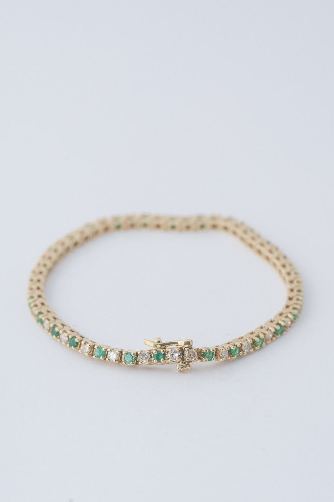 Gold tennis bracelet with emeralds and diamonds