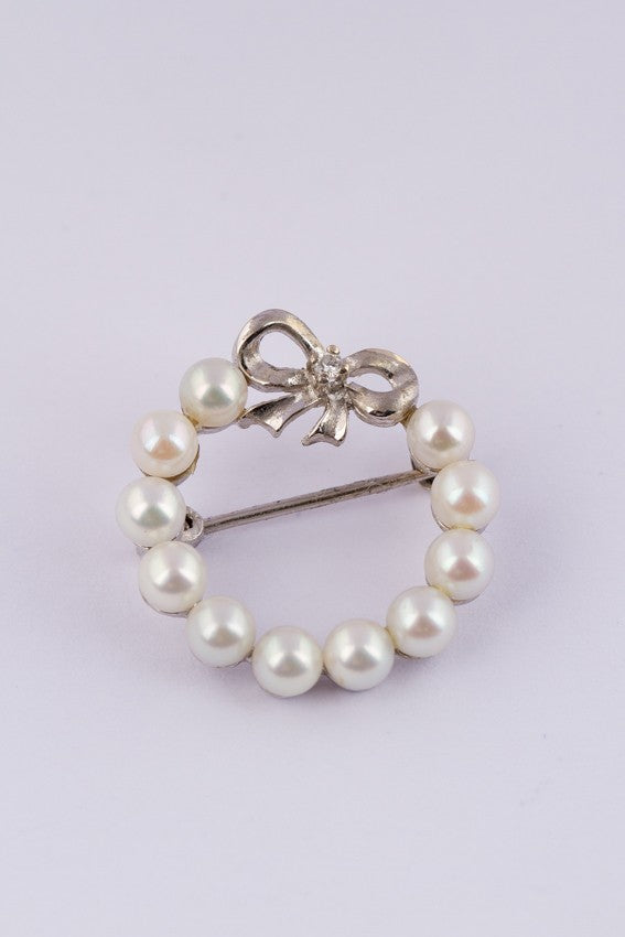 White gold bow brooch with a brilliant and pearls