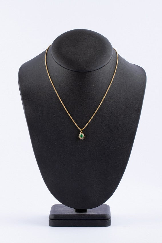 Gold entourage pendant with an emerald and diamonds.