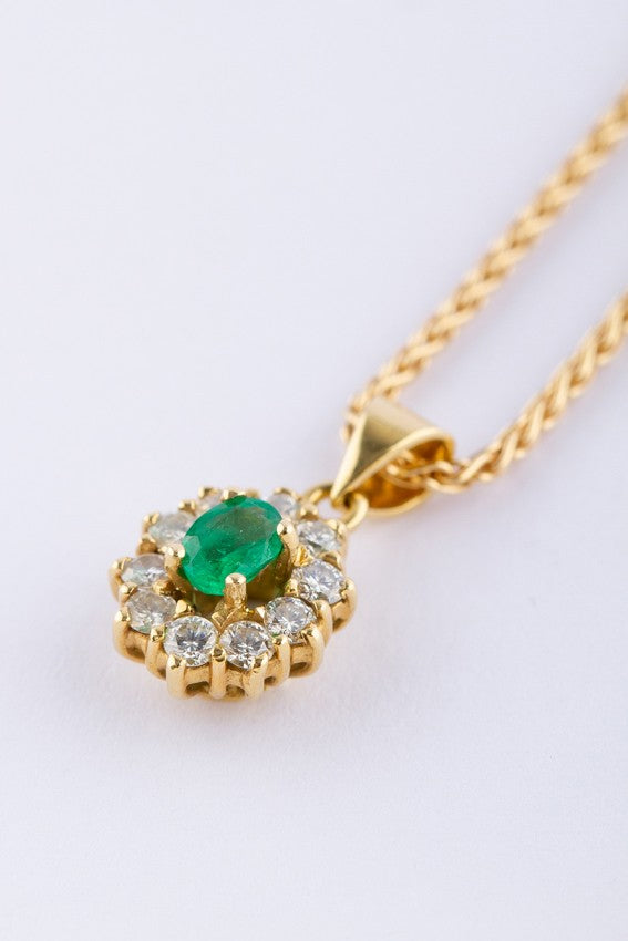 Gold entourage pendant with an emerald and diamonds.