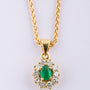 Gold entourage pendant with an emerald and diamonds.