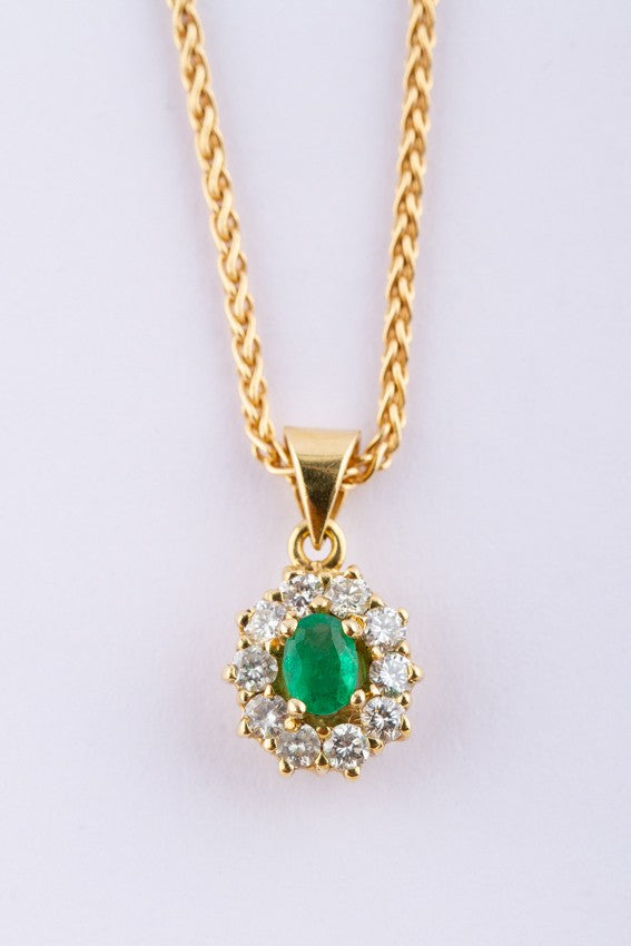 Gold entourage pendant with an emerald and diamonds.