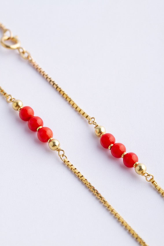 Gouden collier met bloedkoralen tussen schakels.