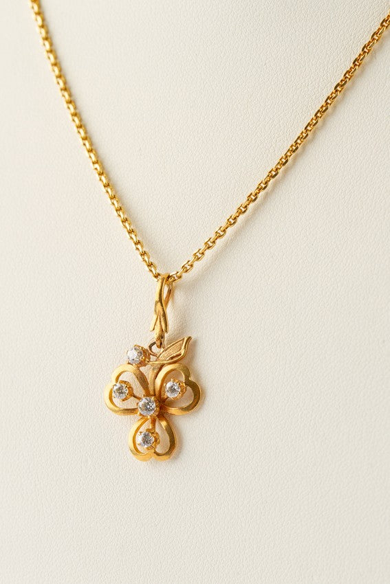 Gold three-leaf clover pendant with diamonds on a gold necklace