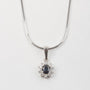 White gold entourage pendant with sapphire and brilliant cut diamonds on a white gold necklace