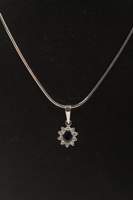 White gold entourage pendant with sapphire and brilliant cut diamonds on a white gold necklace