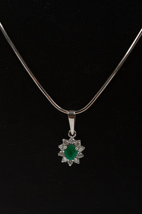 White gold entourage pendant with emerald and diamonds on a white gold necklace