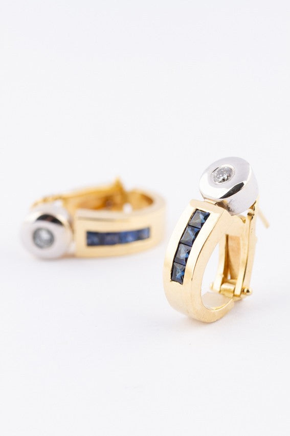 Wit/geel gouden oorknoppen met briljant en carré geslepen saffier