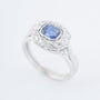 White gold entourage ring with a cushion sapphire and diamonds