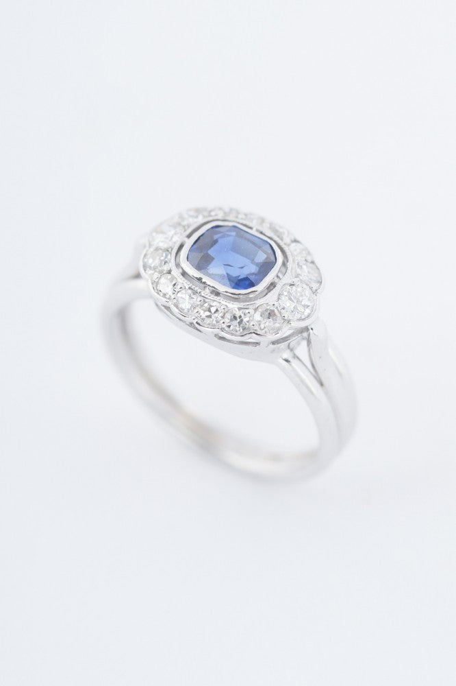 White gold entourage ring with a cushion sapphire and diamonds