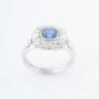 White gold entourage ring with a cushion sapphire and diamonds