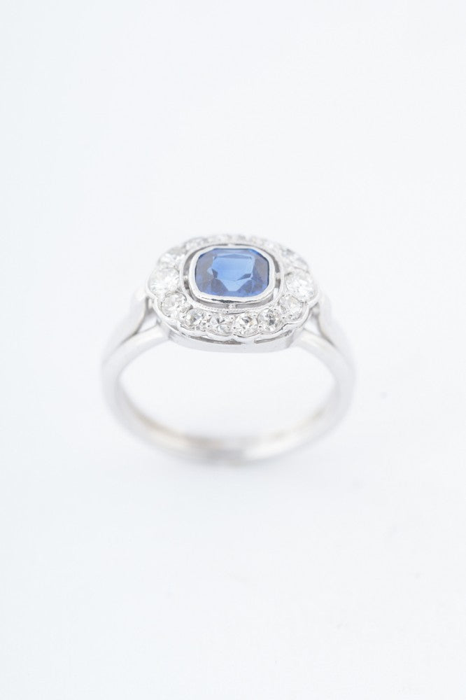White gold entourage ring with a cushion sapphire and diamonds