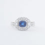 White gold entourage ring with a cushion sapphire and diamonds