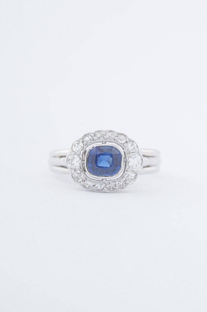 White gold entourage ring with a cushion sapphire and diamonds
