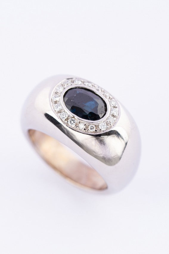 White gold entourage ring with sapphire and diamonds.