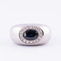White gold entourage ring with sapphire and diamonds.
