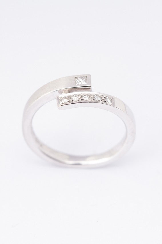 Wit gouden gematteerde slag ring met een prinses geslepen briljant van en rond geslepen briljanten