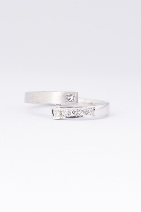 Wit gouden gematteerde slag ring met een prinses geslepen briljant van en rond geslepen briljanten